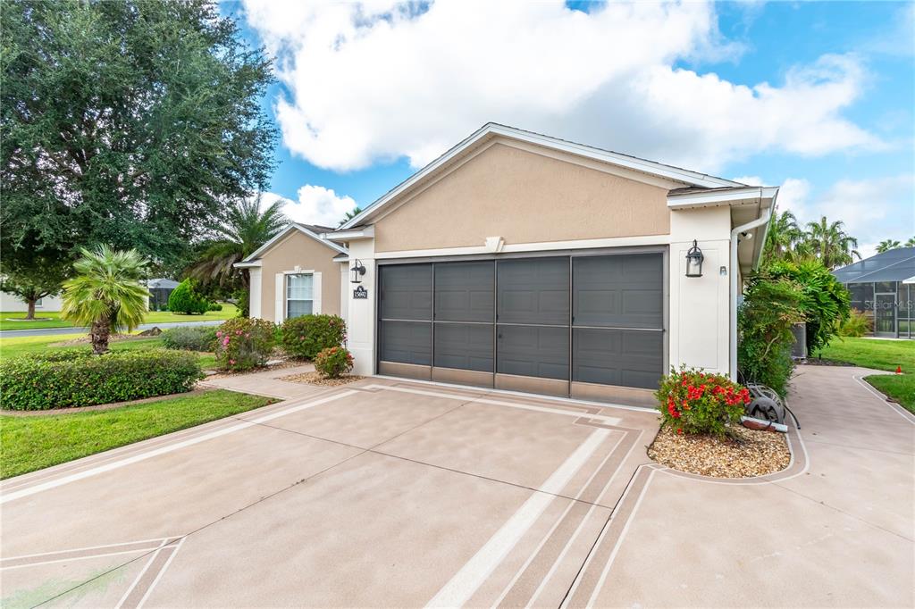 A beige house exterior features a three-car garage with screen doors and a paved driveway — 15692 SW 11TH COURT ROAD, OCALA, FL