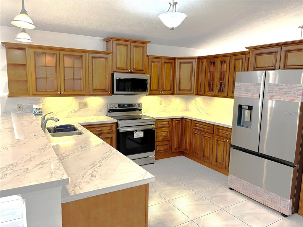 A kitchen features wood cabinets, stainless steel appliances, and white marble-patterned countertops — 510 SW 181ST WAY, PEMBROKE PINES, FL