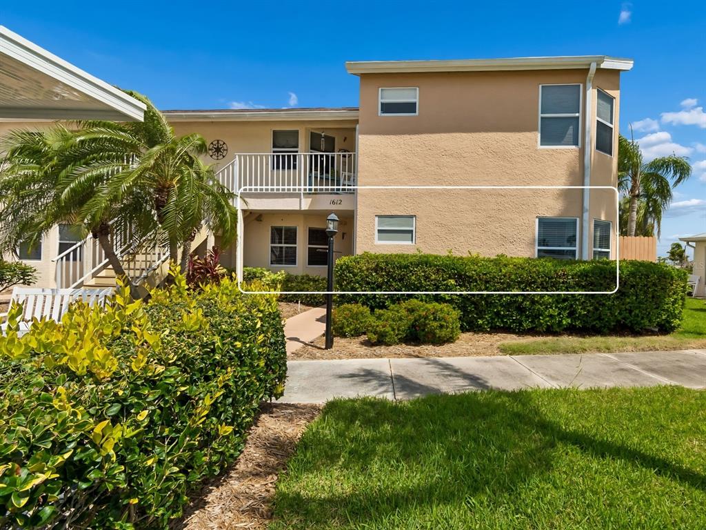 A two-story tan stucco building with a wooden privacy fence and a manicured hedge — 1612 FAIRWAY TRACE UNIT A, PALMETTO, FL