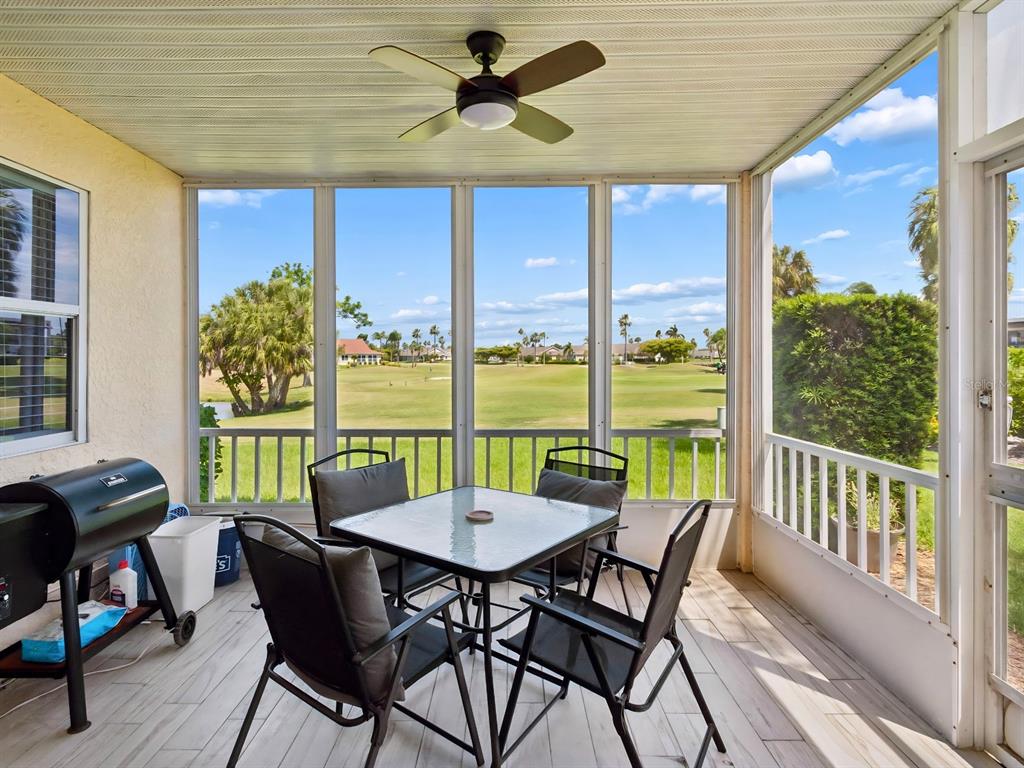 A screened-in patio features a dining set, a grill, and views of a golf course — 1612 FAIRWAY TRACE UNIT A, PALMETTO, FL