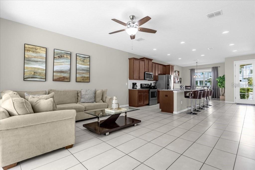 An open-concept living room and kitchen with tile flooring, a ceiling fan, and cabinetry — 1540 CAREY PALM CIRCLE, KISSIMMEE, FL