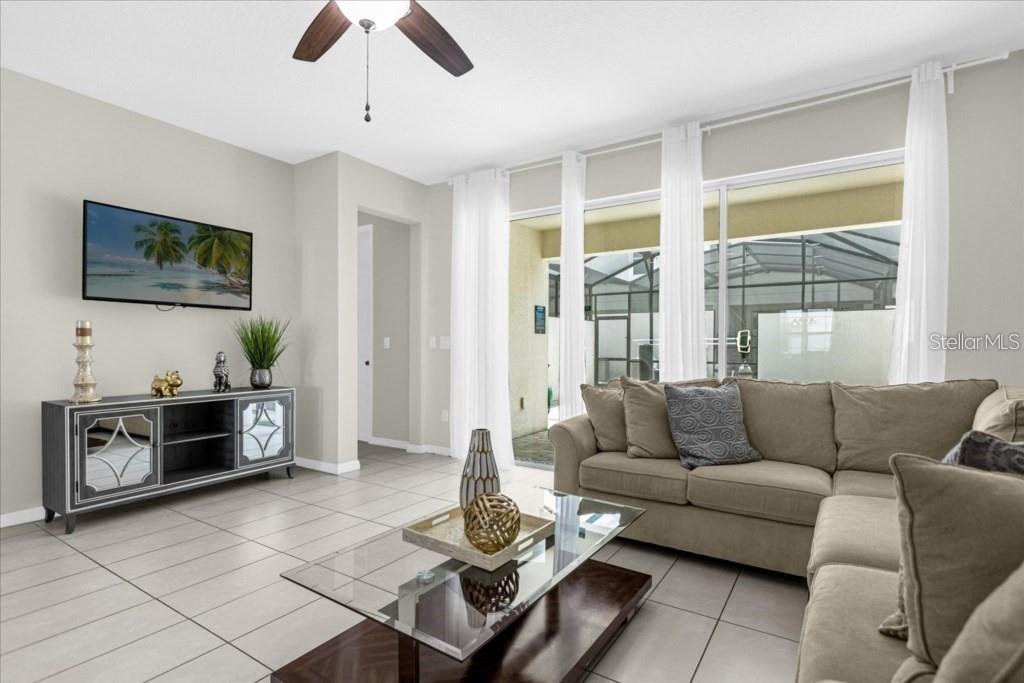 A living room features a beige sectional sofa, a glass coffee table, and tile flooring — 1540 CAREY PALM CIRCLE, KISSIMMEE, FL