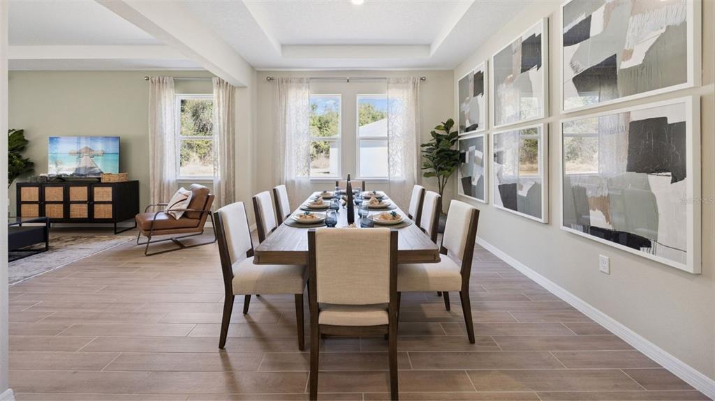 A dining room features a long wooden table, upholstered chairs, and large abstract wall art — 3050 KINGSMAN TRAIL, ORMOND BEACH, FL