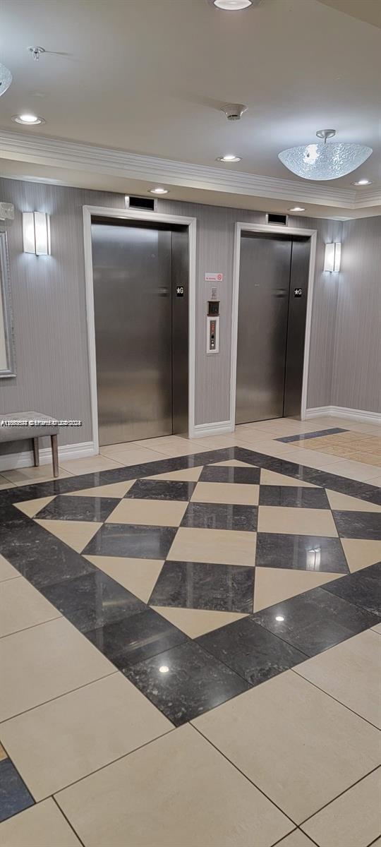An elevator lobby features stainless steel doors, gray striped wallpaper, and a patterned tile floor — HOLLYWOOD, FL