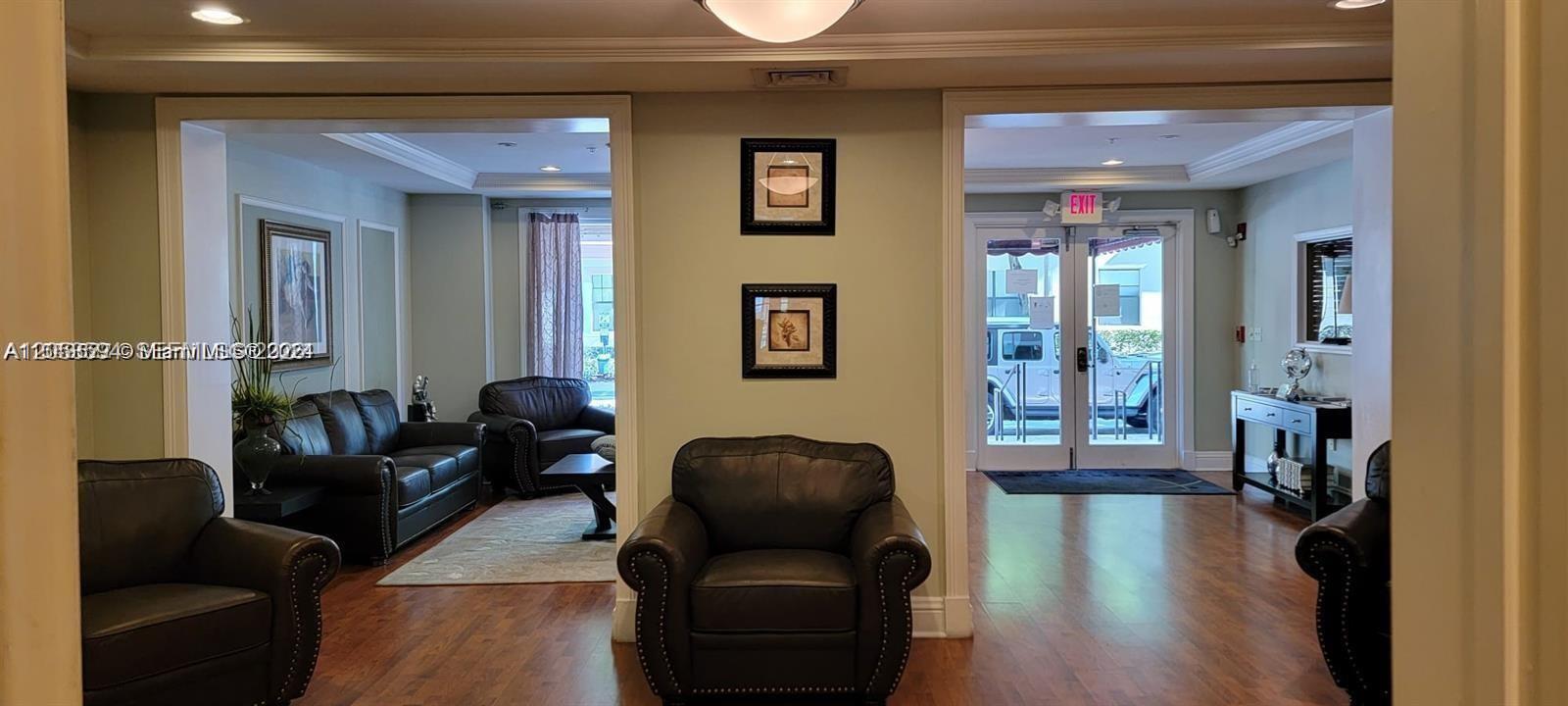 A lobby features leather armchairs, a sofa, framed wall art, and glass exit doors — HOLLYWOOD, FL