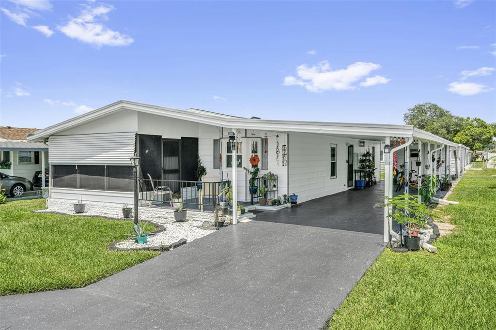 A white mobile home features a screened-in porch, a paved driveway, and a covered carport — 6666 BRIARHILL DRIVE NE, WINTER HAVEN, FL