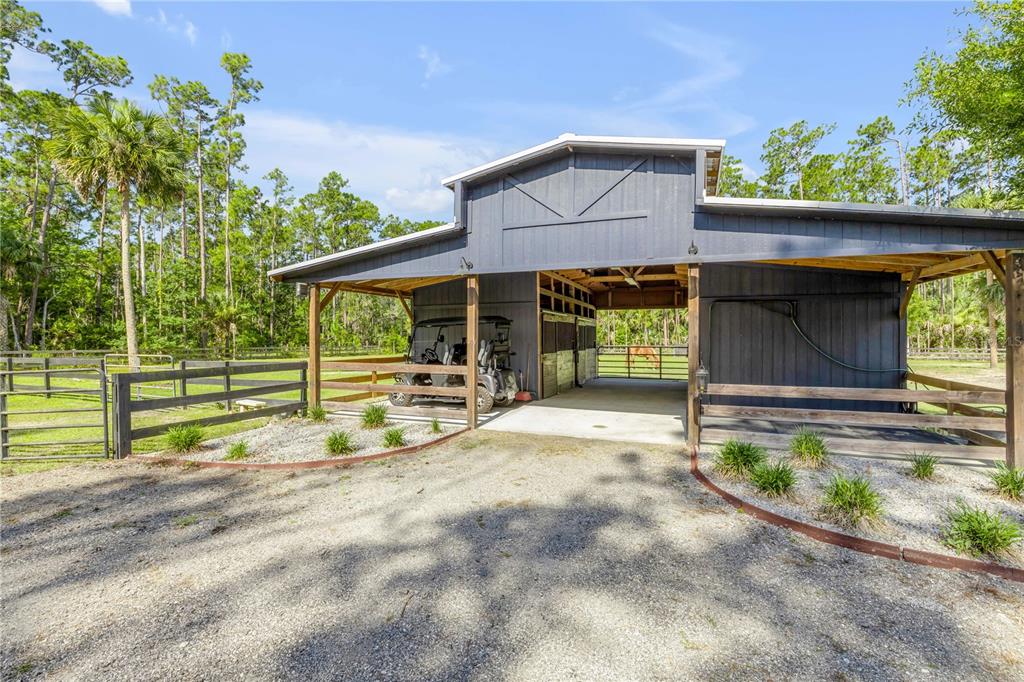 A dark gray barn with a gravel driveway and a golf cart parked inside — 2195 W POINSETTIA DRIVE, PORT ORANGE, FL