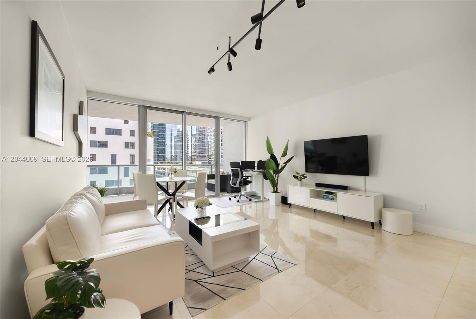 A bright living room features white tile floors, a modern sofa, and a balcony view — 1331 Brickell Bay Dr # 904, Miami FL 33131, MIAMI, FL