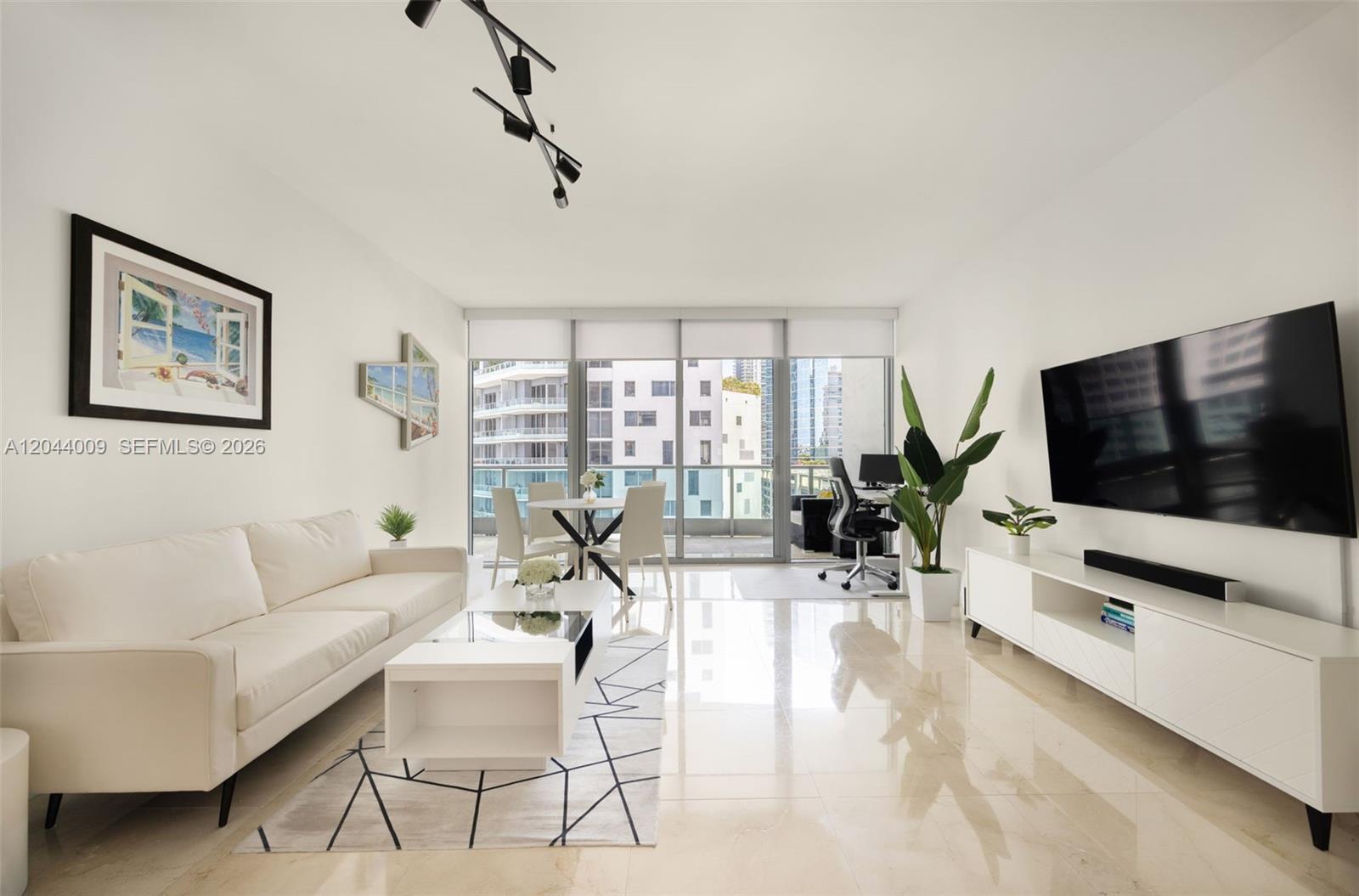 A modern living room features a white sofa, coffee table, media console, and balcony access — 1331 Brickell Bay Dr # 904, Miami FL 33131, MIAMI, FL