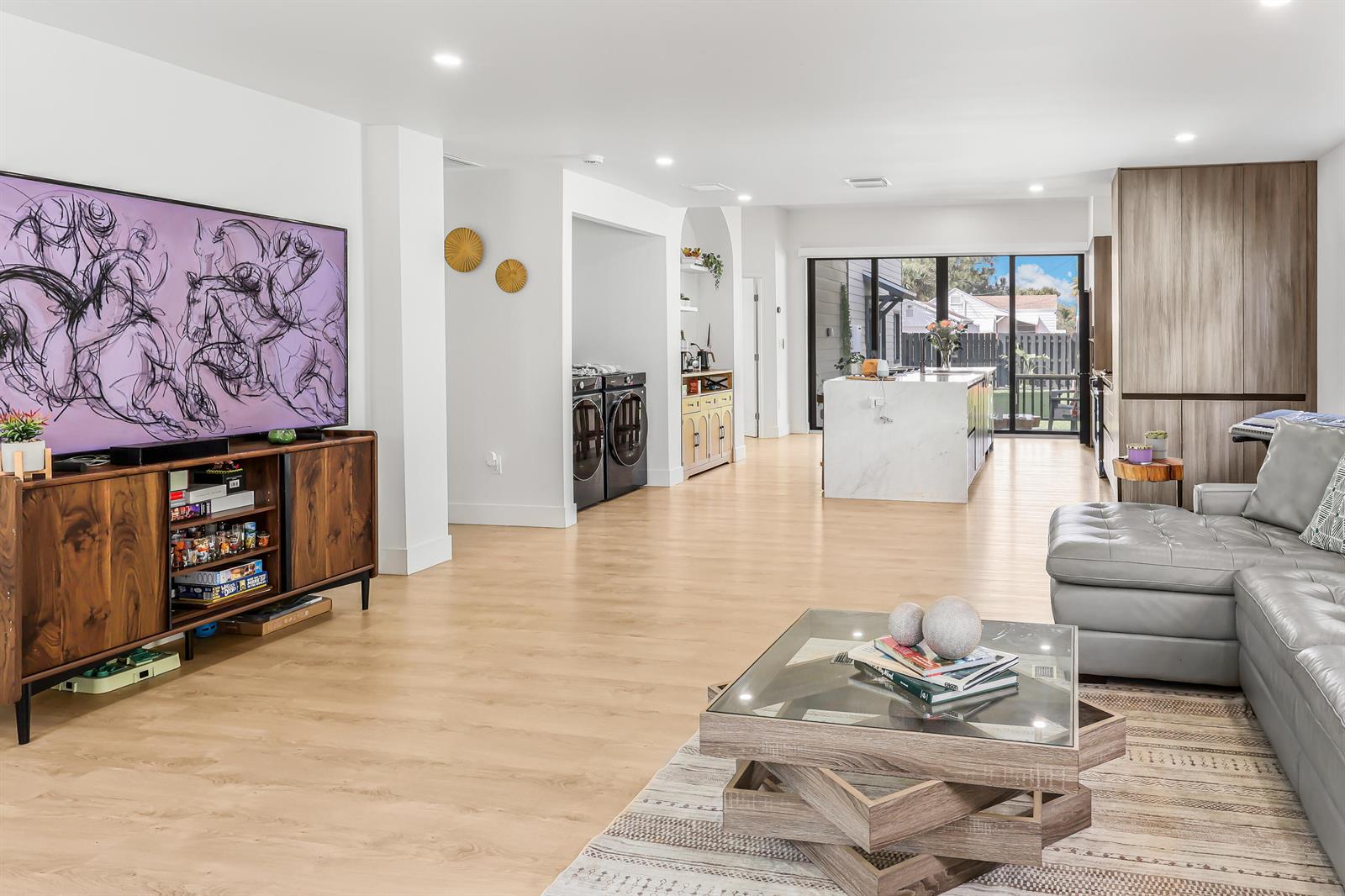A modern open-concept living room and kitchen featuring light wood floors and a marble island — 1125 N K Street, FL 33460, FL