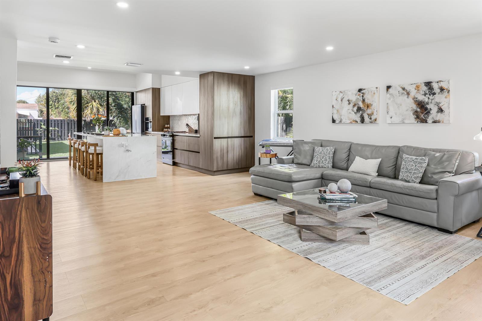 An open-concept living room and kitchen featuring light wood floors, a marble island, and sofa — 1125 N K Street, FL 33460, FL