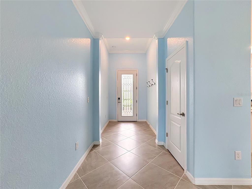 A bright entryway features light blue walls, tile flooring, and a white front door — 10185 COLUBRINA DRIVE, VENICE, FL