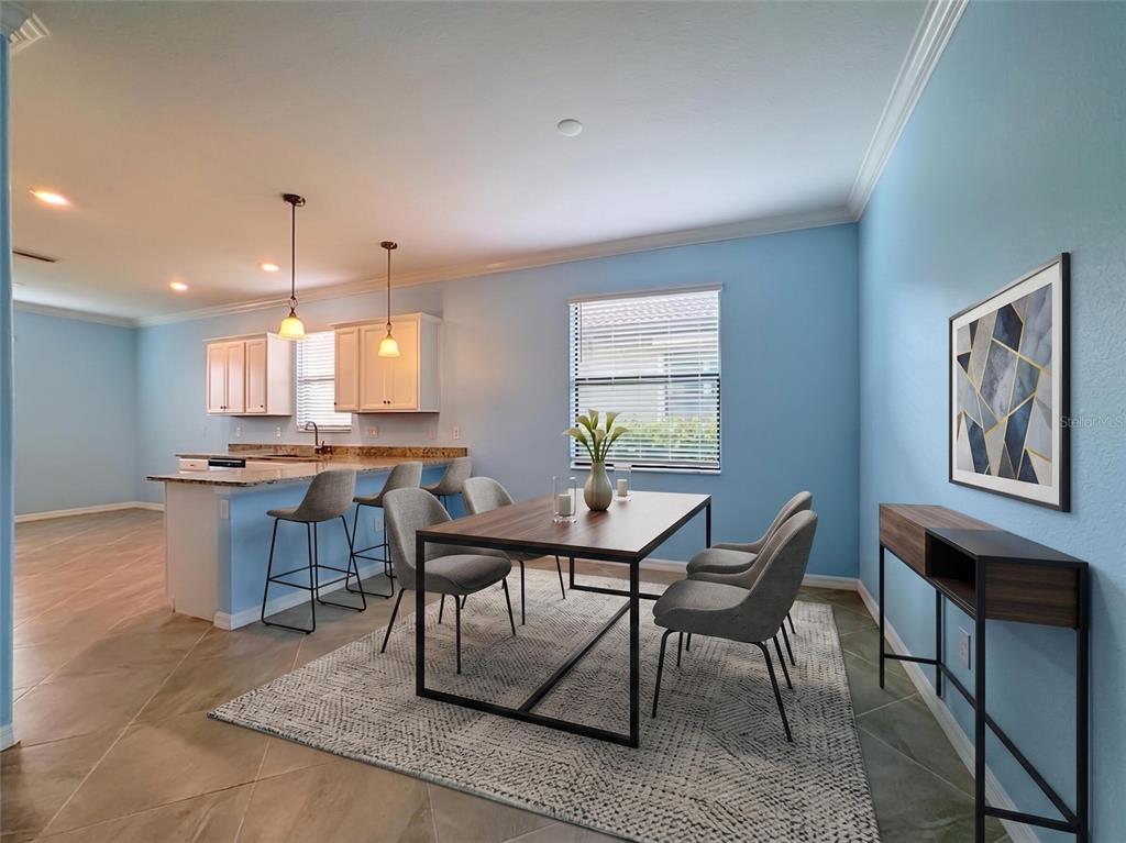 A dining area with a table and chairs sits adjacent to a kitchen with bar seating — 10185 COLUBRINA DRIVE, VENICE, FL