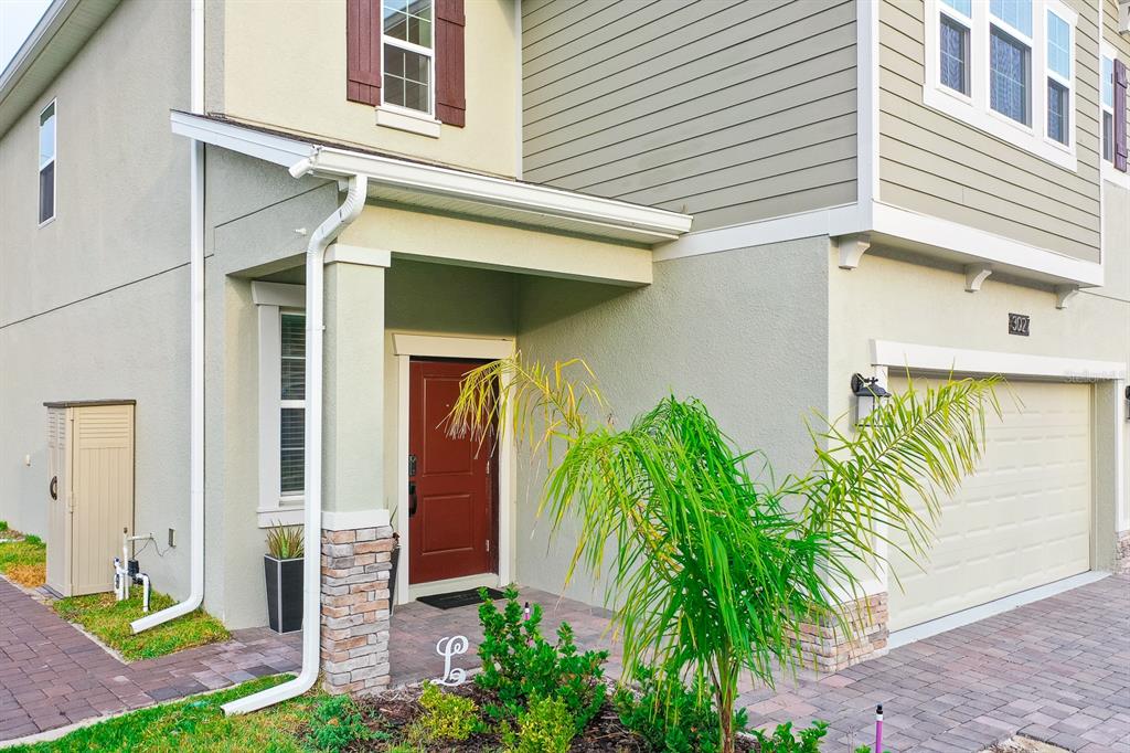 A two-story house exterior features a red front door, a garage, and a small palm — 3027 CAMDEN WAY, DAVENPORT, FL