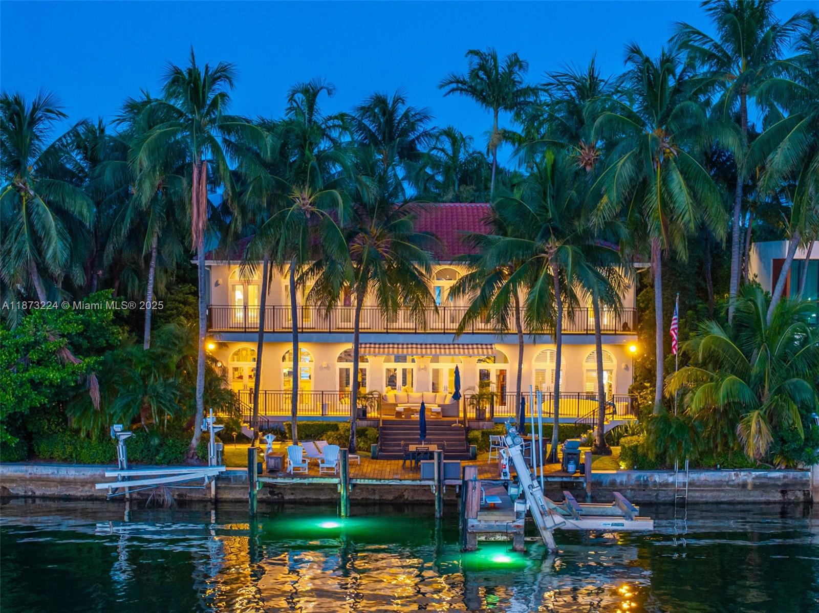 A two-story waterfront house with a dock, palm trees, and illuminated balconies at dusk — 814 W Dilido Dr, Miami Beach FL 33139, MIAMI BEACH, FL