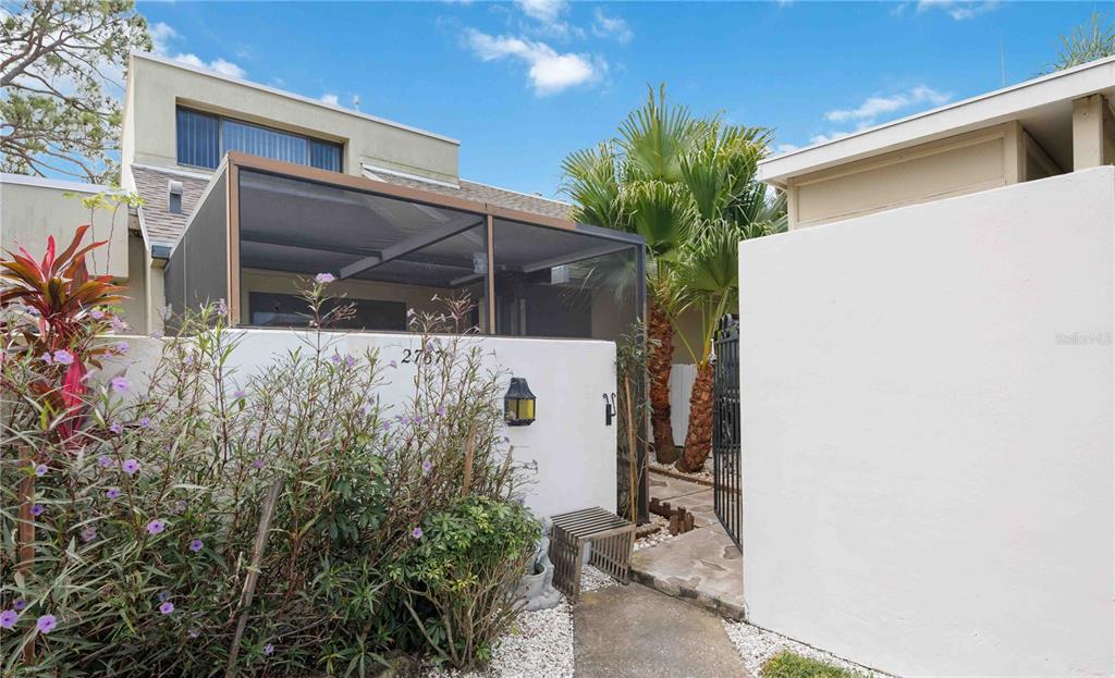 A view of a home exterior featuring a screened-in porch, white walls, and landscaping — 2767 HORSESHOE COURT UNIT Q-3, SARASOTA, FL