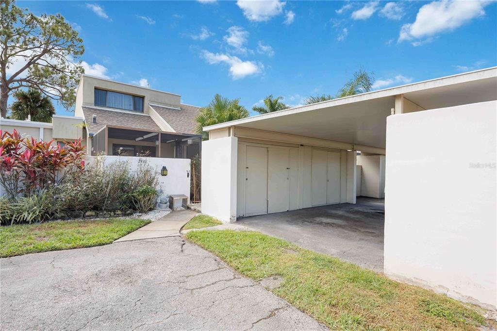 A concrete driveway leads to a covered carport next to a multi-story residential building — 2767 HORSESHOE COURT UNIT Q-3, SARASOTA, FL