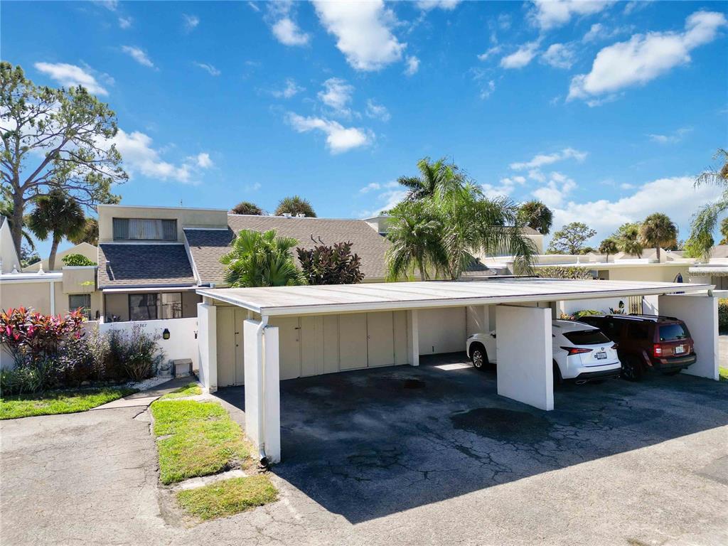 A covered carport sits in front of a multi-story residential building with a shingled roof — 2767 HORSESHOE COURT UNIT Q-3, SARASOTA, FL