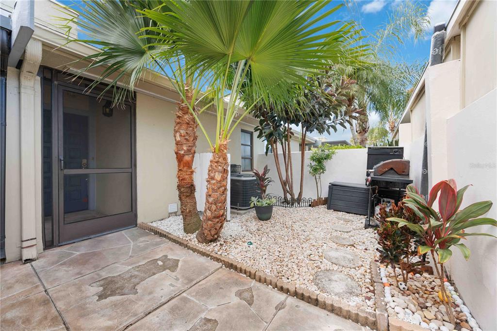 A small outdoor patio features a stone floor, gravel landscaping, palm trees, and a grill — 2767 HORSESHOE COURT UNIT Q-3, SARASOTA, FL