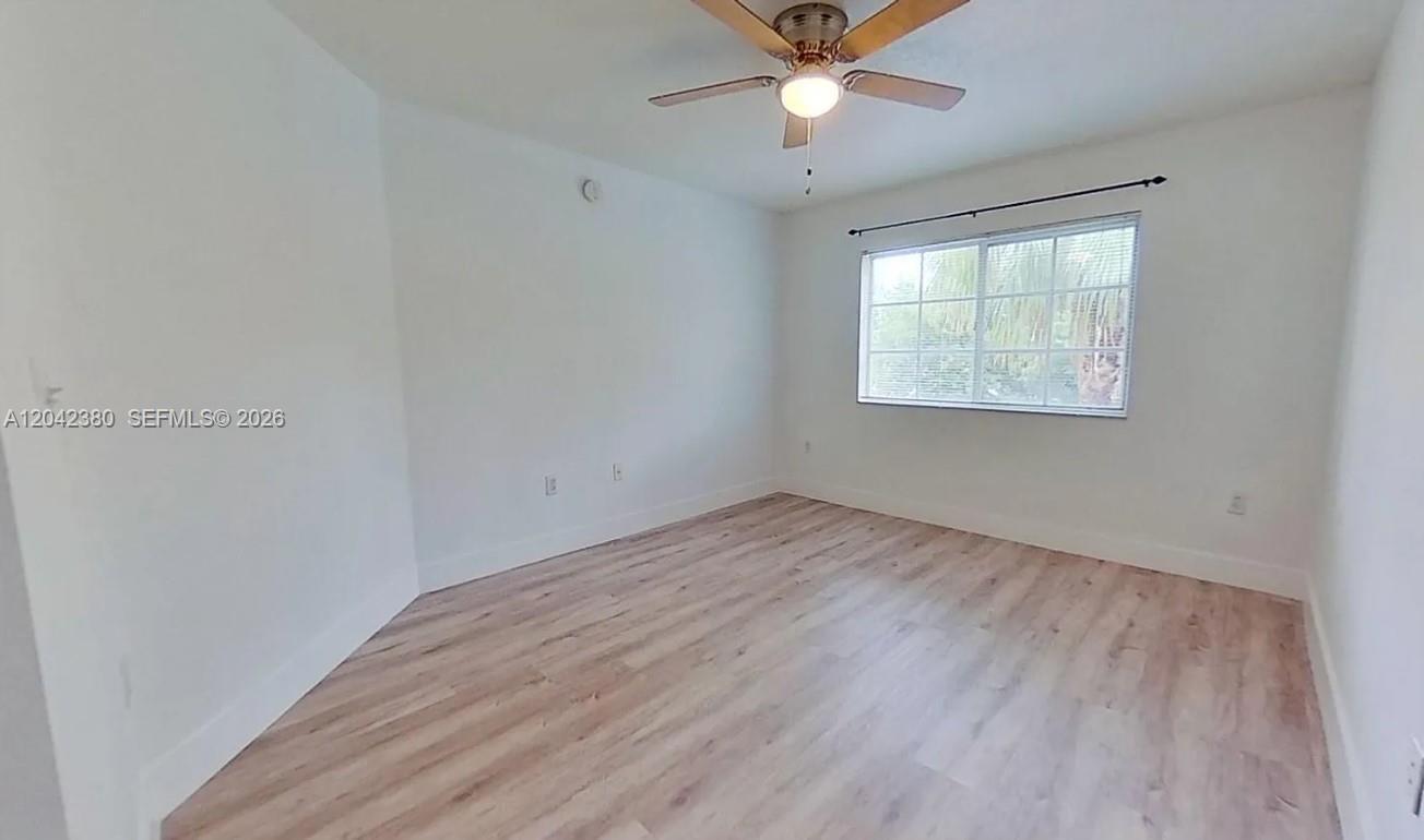 An empty bedroom features light wood-look flooring, white walls, and a ceiling fan — 2544 Centergate Dr # 303, Miramar FL 33025, MIRAMAR, FL