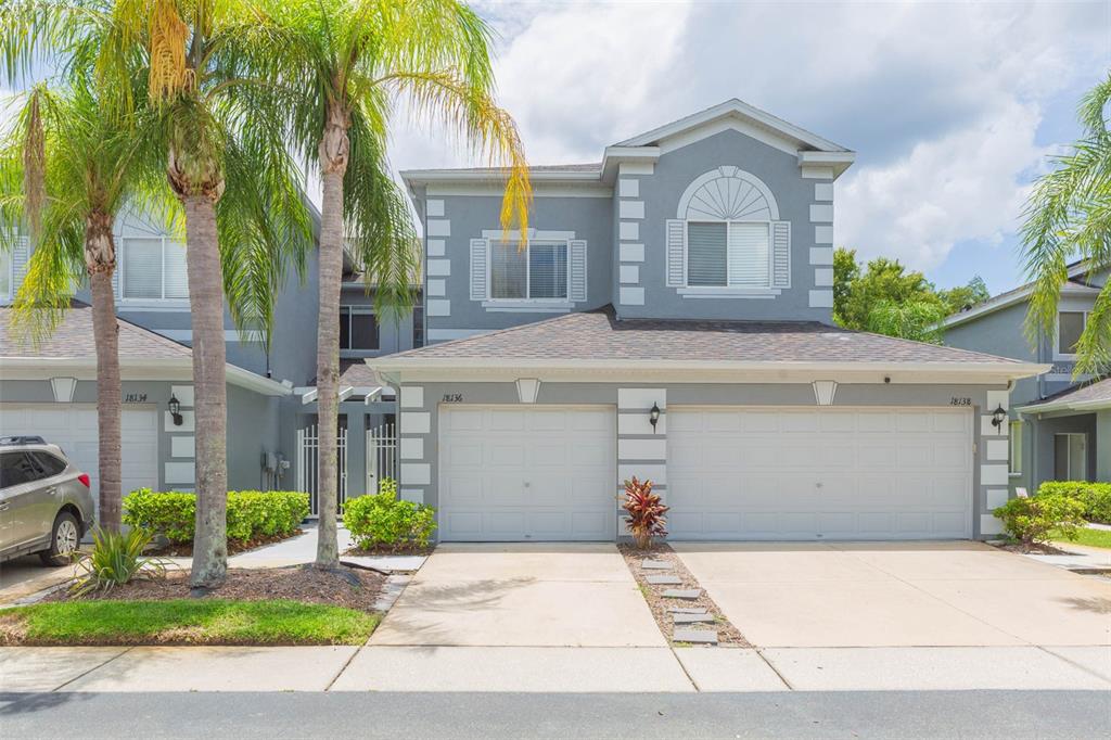 A two-story gray townhouse with a two-car garage and palm trees in the front yard — 18136 NASSAU POINT DRIVE, TAMPA, FL