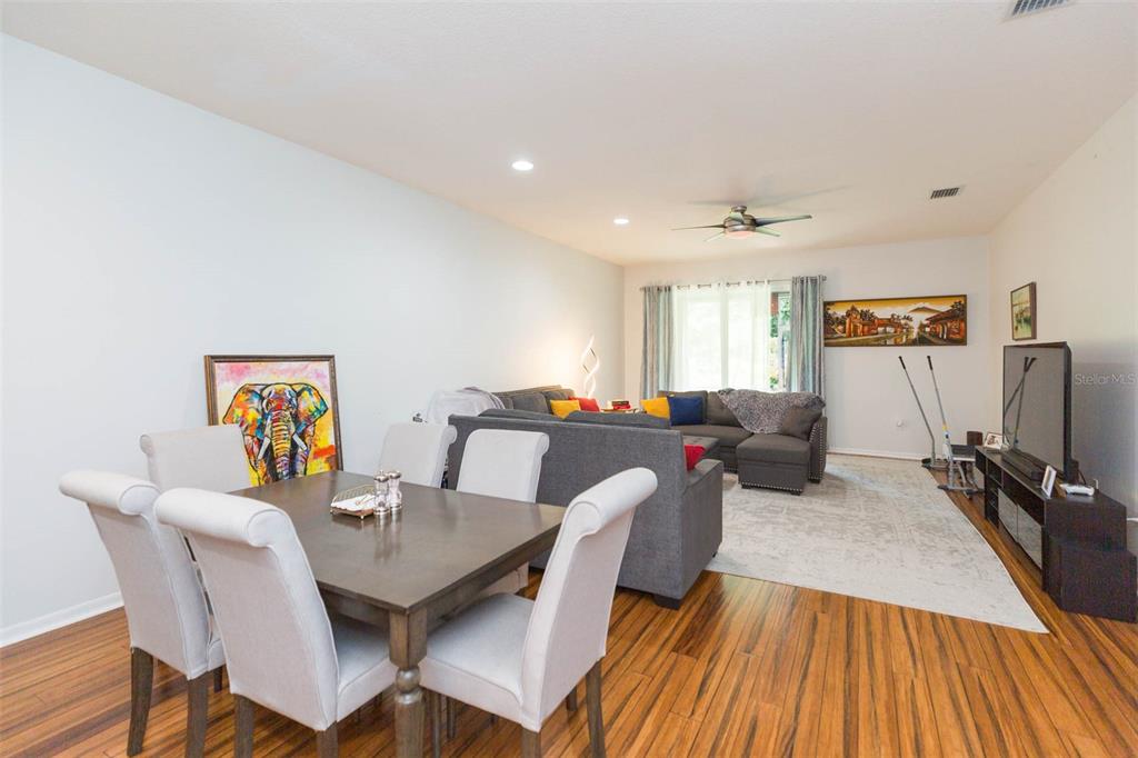 An open-concept living and dining area features wood-look flooring, a gray sectional, and a dining set — 18136 NASSAU POINT DRIVE, TAMPA, FL