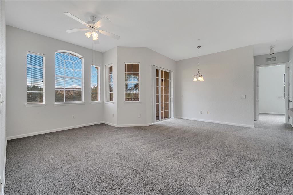 An empty room with gray carpet, a ceiling fan, large windows, and a sliding door — 817 TERRACE RIDGE CIRCLE UNIT 817, DAVENPORT, FL