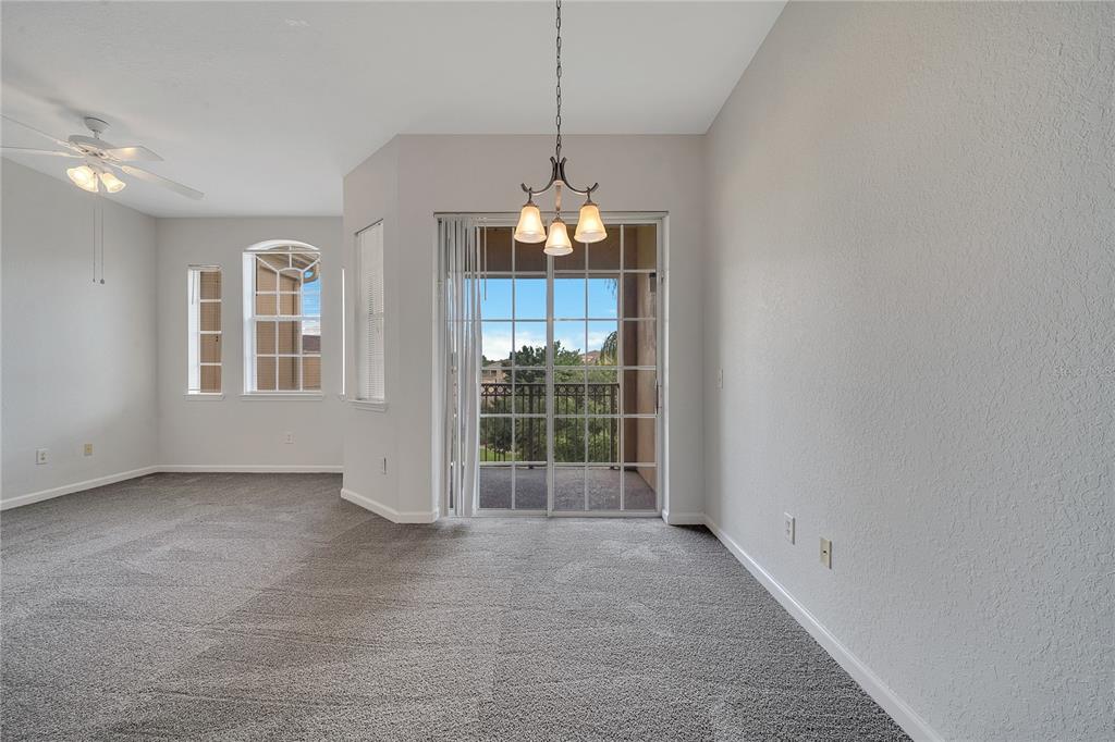 A carpeted dining area features a chandelier, sliding glass doors, and windows overlooking a balcony — 817 TERRACE RIDGE CIRCLE UNIT 817, DAVENPORT, FL