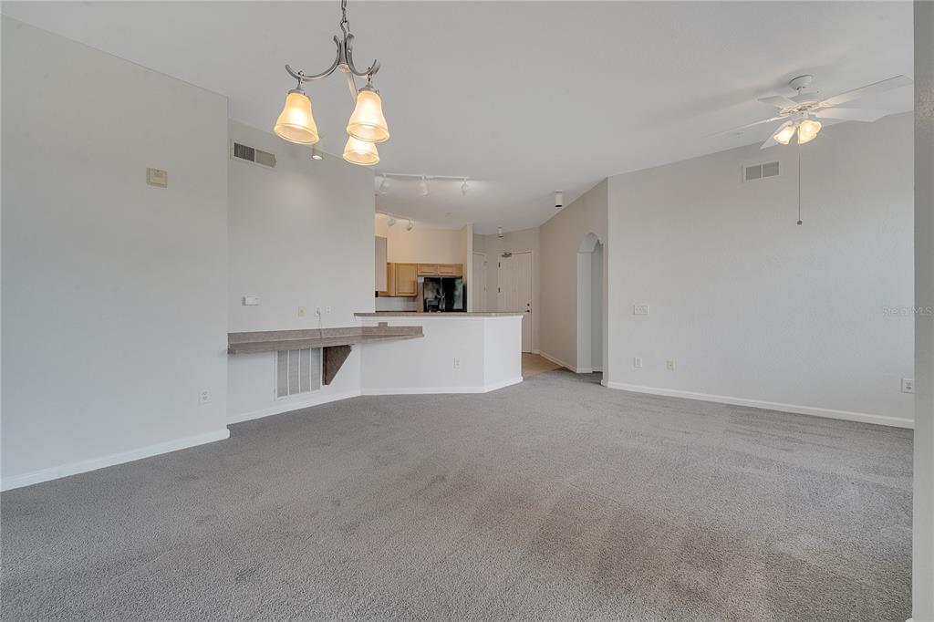 An open-concept living area features gray carpeting, a breakfast bar, and a ceiling fan — 817 TERRACE RIDGE CIRCLE UNIT 817, DAVENPORT, FL