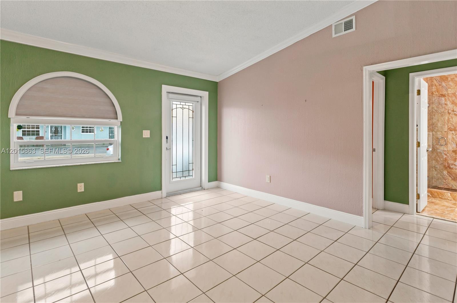 A room with green and pink walls, tile flooring, an arched window, and a door — 5471 W 27th Ct, Hialeah FL 33016, HIALEAH, FL