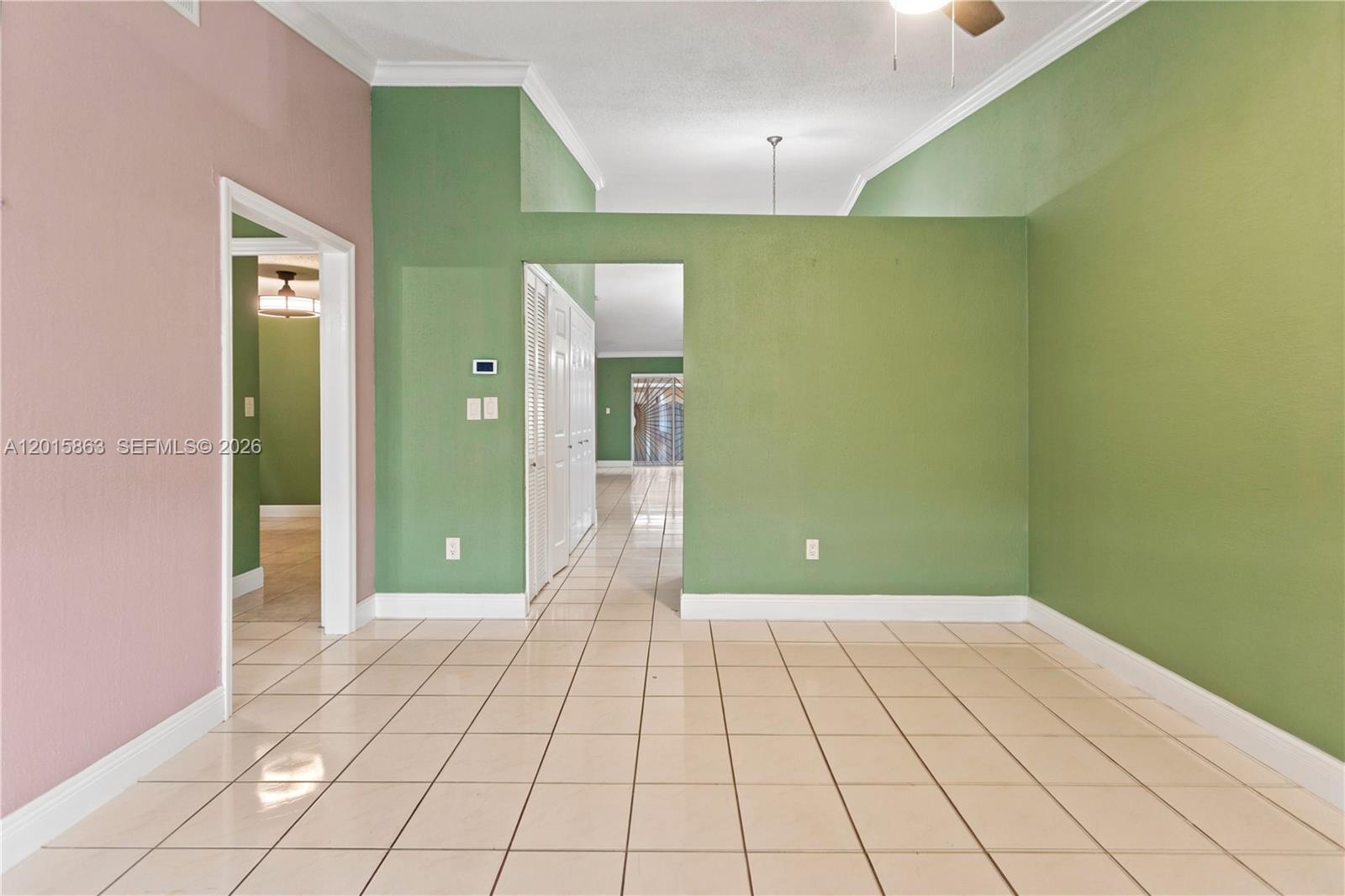 A room with green and pink walls, tiled floors, and a doorway leading to another area — 5471 W 27th Ct, Hialeah FL 33016, HIALEAH, FL