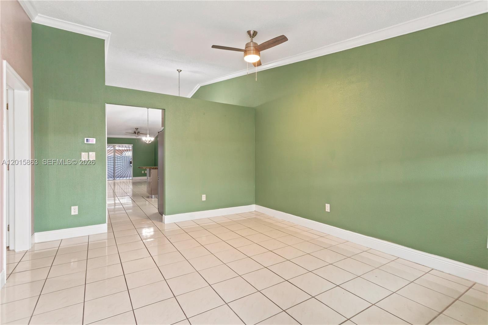 A room with green walls, tile flooring, and a ceiling fan viewed through a doorway — 5471 W 27th Ct, Hialeah FL 33016, HIALEAH, FL