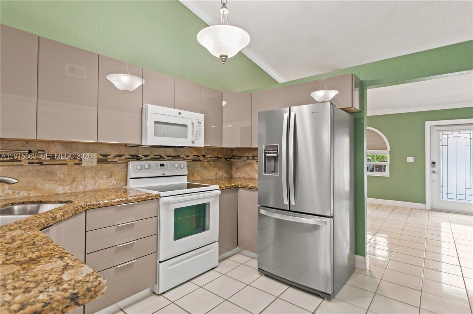 A kitchen features glossy taupe cabinets, granite countertops, stainless steel appliances, and green walls — 5471 W 27th Ct, Hialeah FL 33016, HIALEAH, FL