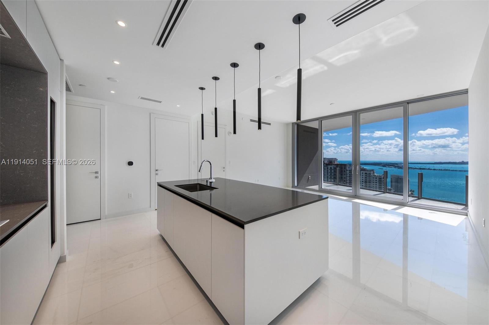 A modern kitchen features a central island with a dark countertop and a water view — 300 Biscayne Boulevard Way # 3506W, Miami FL 33131, MIAMI, FL