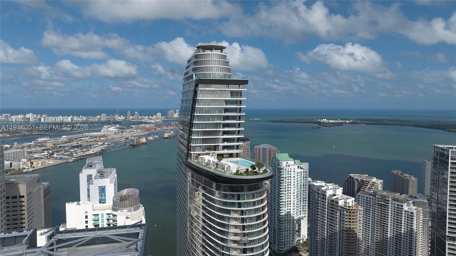An aerial view shows a modern skyscraper with a prominent outdoor pool deck and balconies — 300 Biscayne Boulevard Way # 3506W, Miami FL 33131, MIAMI, FL