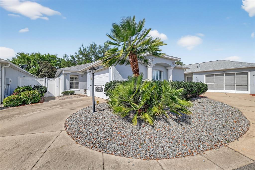A single-story house with a palm tree in a gravel garden and a concrete driveway — 1808 PEACHTREE AVENUE, THE VILLAGES, FL