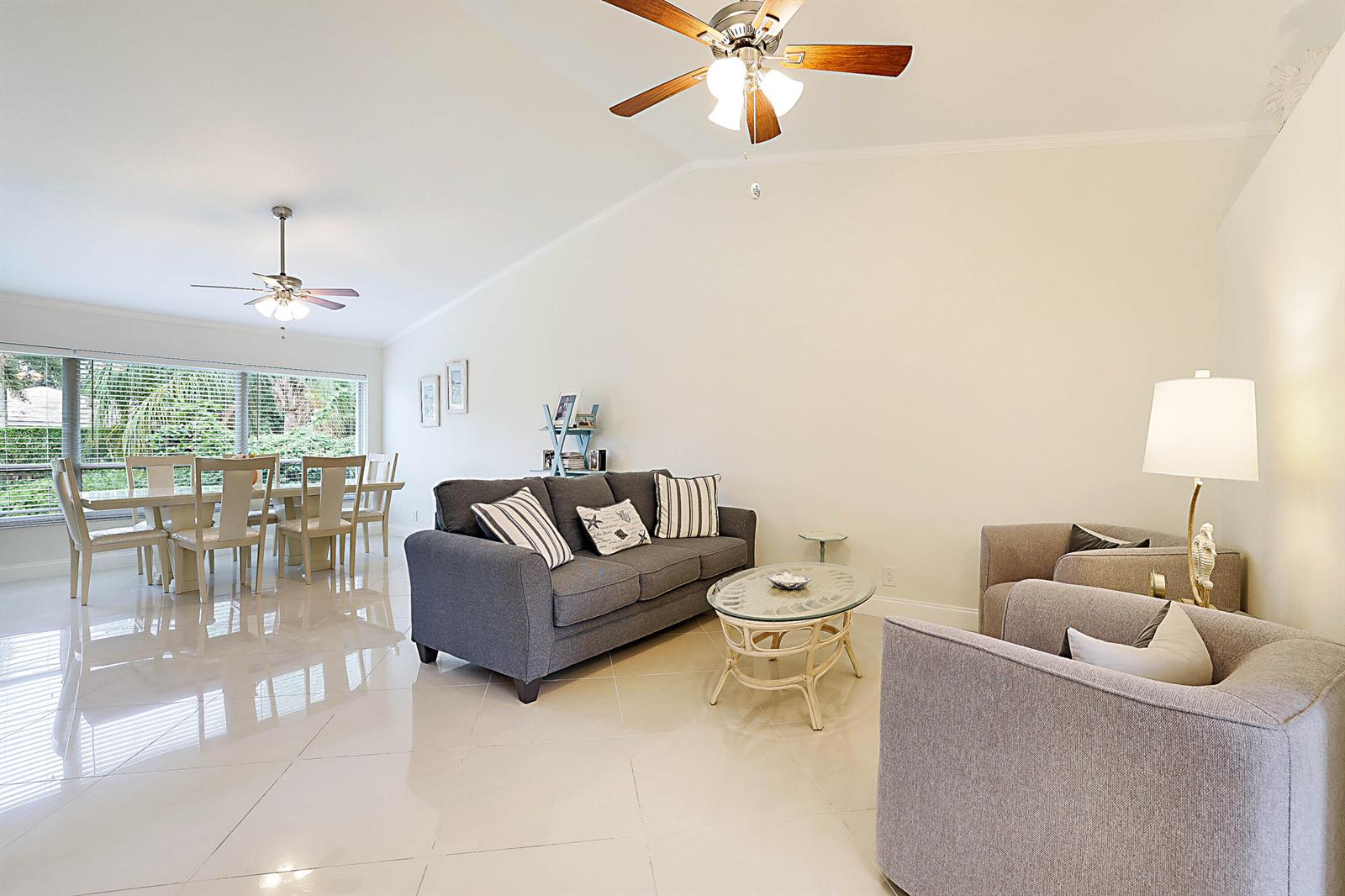 A living room and dining area feature light tile floors, vaulted ceilings, and ceiling fans — 8753 SE Riverfront Terrace, Jupiter FL 33469, JUPITER, FL