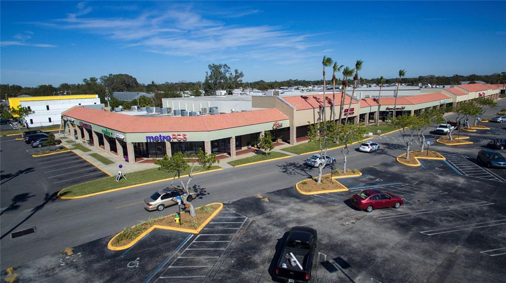 An aerial view shows a commercial strip mall with a parking lot and palm trees — 6501 102ND AVENUE N, PINELLAS PARK, FL