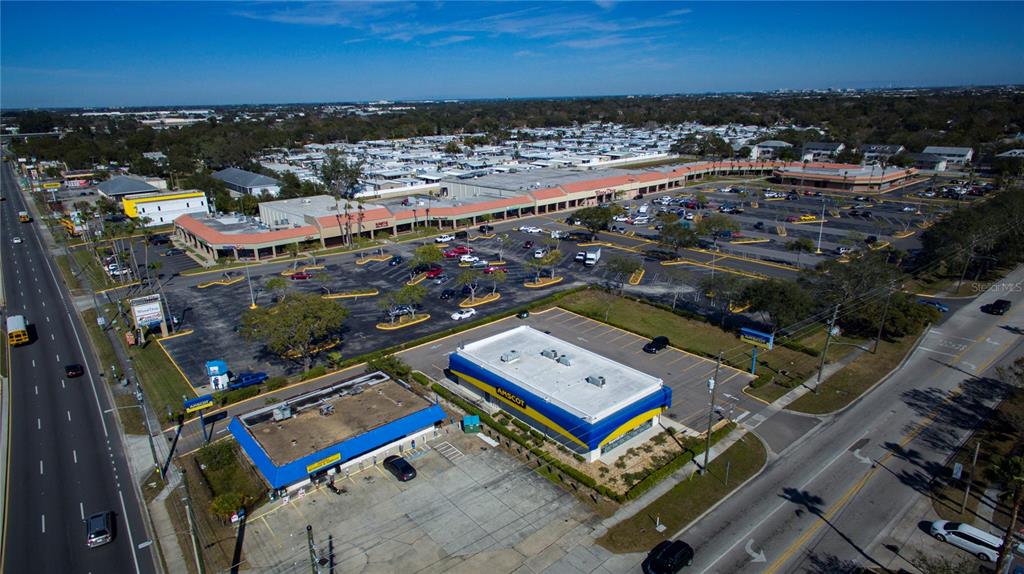 An aerial view shows a commercial shopping center with a large parking lot and Amscot building — 6501 102ND AVENUE N, PINELLAS PARK, FL