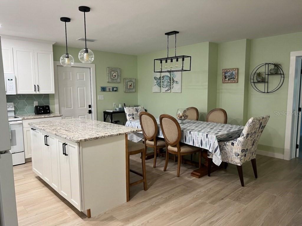 A kitchen with a granite-topped island and a dining area with light green walls — 311 66TH STREET, BRADENTON BEACH, FL