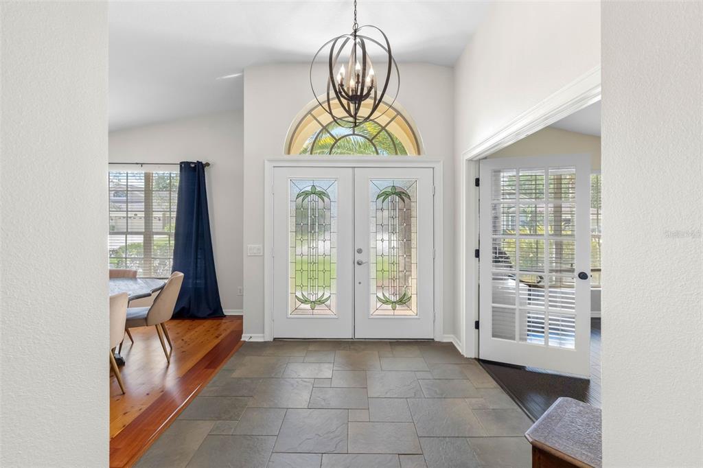 An entryway features a tiled floor, double glass-paneled doors, and a decorative orb chandelier — 9104 CYPRESS KEEP LANE, ODESSA, FL