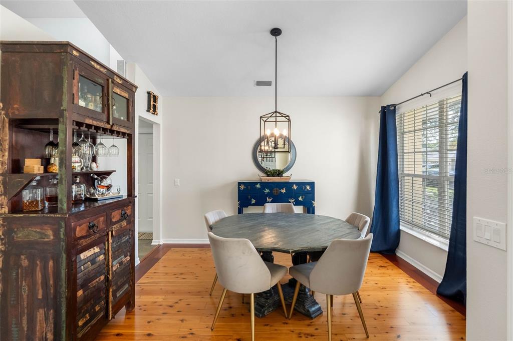 A dining room with a round wooden table, four chairs, and a large rustic cabinet — 9104 CYPRESS KEEP LANE, ODESSA, FL