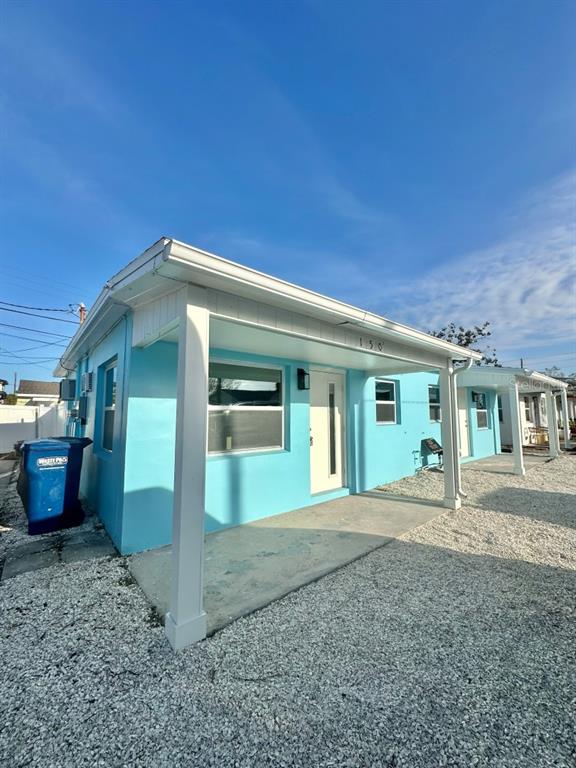 A bright blue, single-story exterior with a covered front porch and white trim — 150 147TH AVENUE E, MADEIRA BEACH, FL
