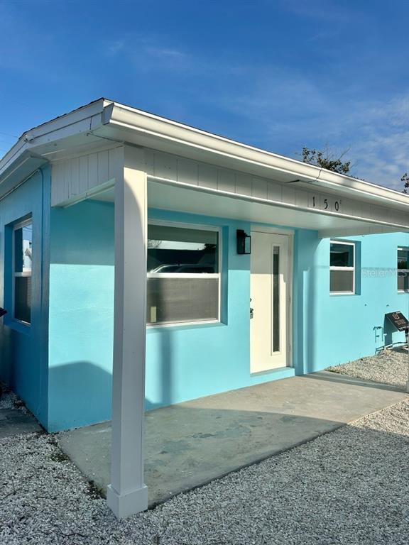 A light blue exterior house with a covered concrete porch and a white front door — 150 147TH AVENUE E, MADEIRA BEACH, FL