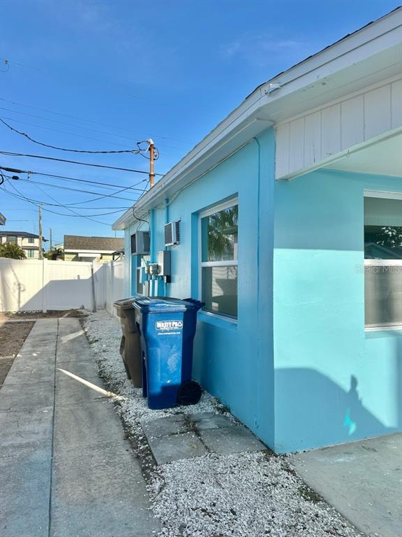 A light blue exterior wall features two windows, electrical equipment, and two trash bins outside — 150 147TH AVENUE E, MADEIRA BEACH, FL
