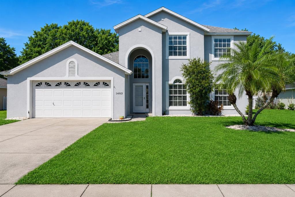A two-story house with a gray stucco exterior, a two-car garage, and a palm tree — 1483 SURREY PARK DRIVE, PORT ORANGE, FL