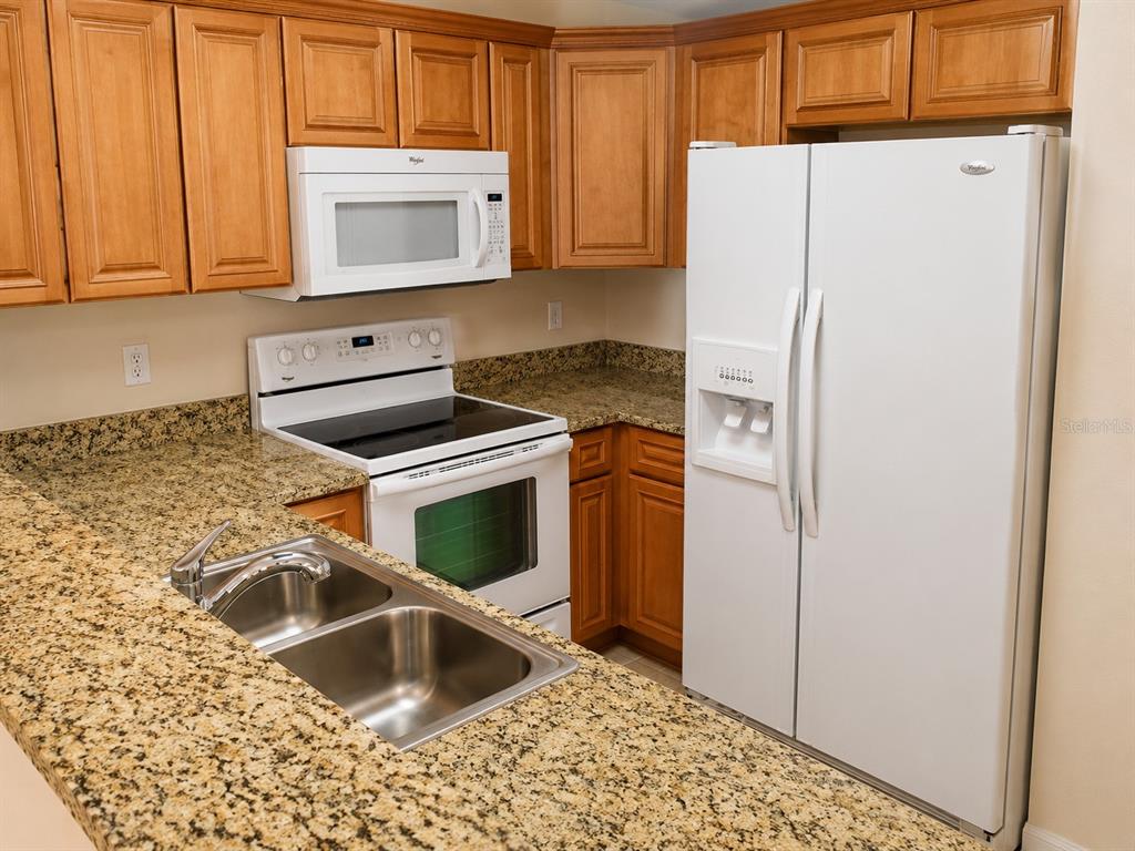A kitchen features wood cabinets, granite countertops, white appliances, and a double-basin sink — 518 NW 39 ROAD, GAINESVILLE, FL