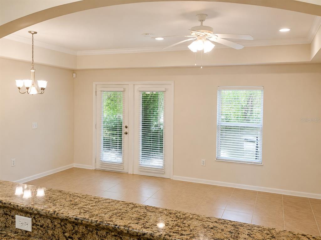 A dining area with tile floors, a ceiling fan, a chandelier, and glass patio doors — 518 NW 39 ROAD, GAINESVILLE, FL