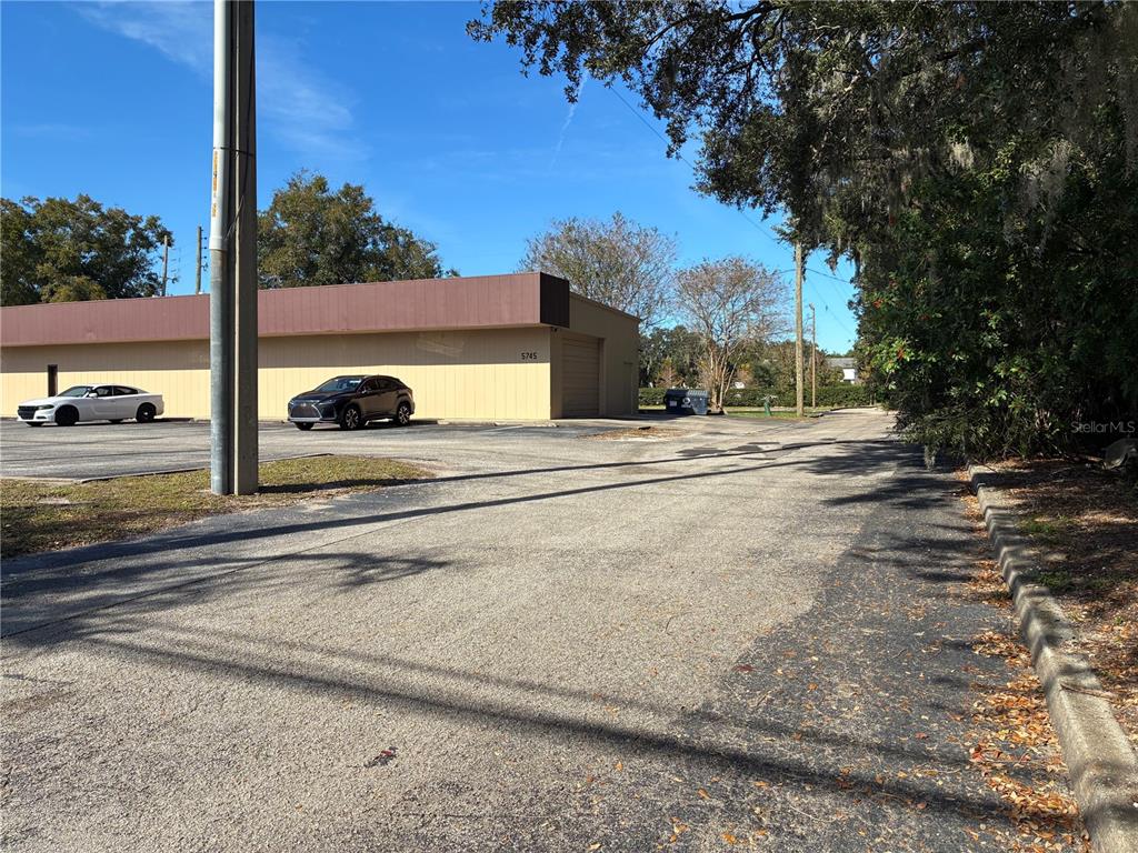 A single-story commercial building with a tan facade and brown trim sits beside a parking lot — 5745 PERSHING AVENUE, ORLANDO, FL
