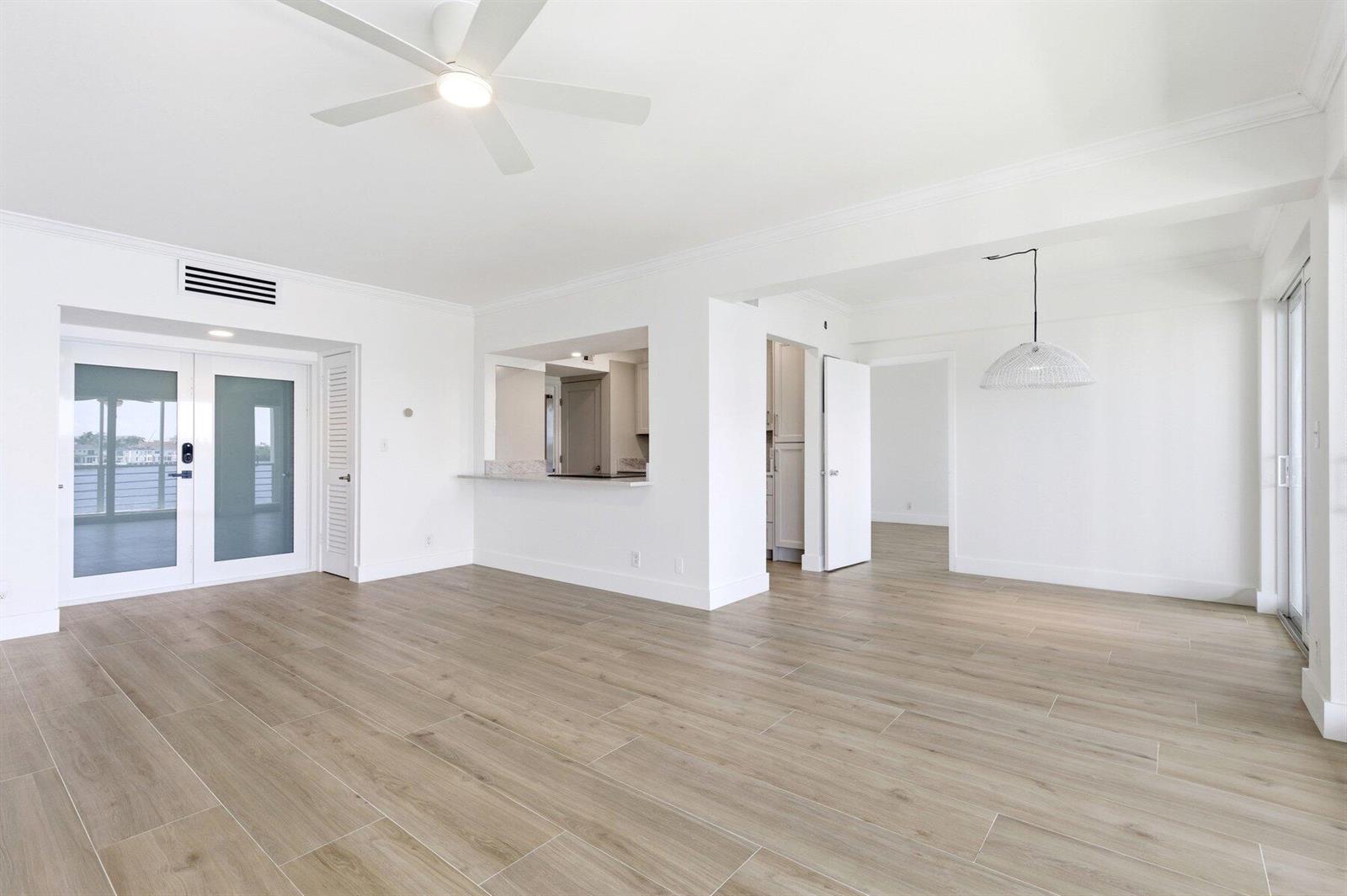 An empty living room with light wood-look tile flooring, a ceiling fan, and a pass-through — 850 NE Spanish River Boulevard # 0240, Boca Raton FL 33431, BOCA RATON, FL